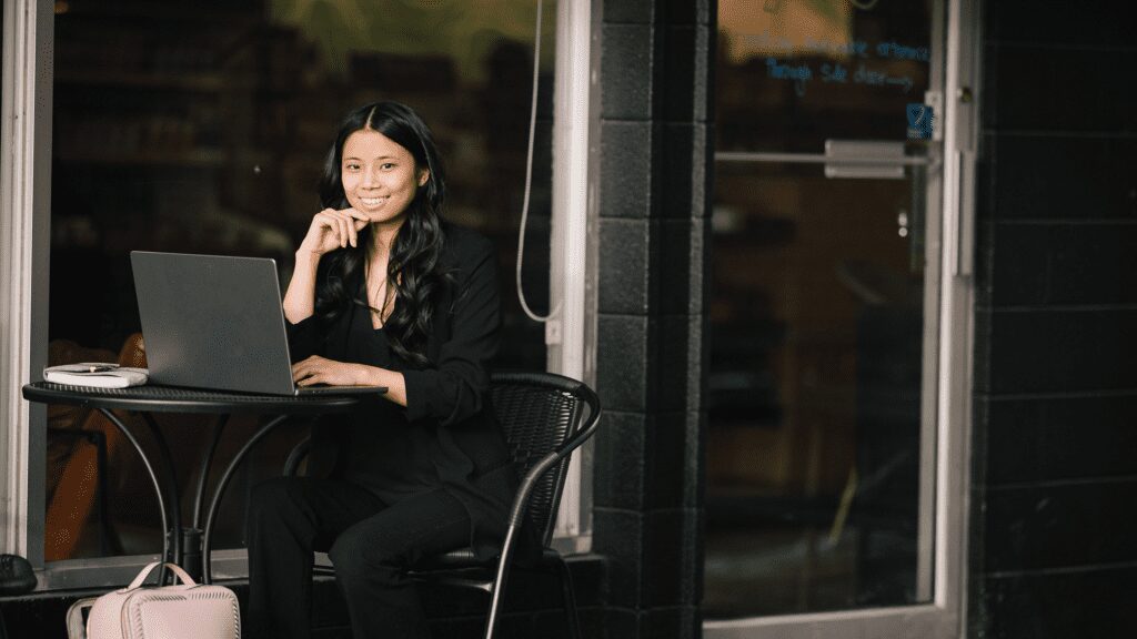 Woman sitting outside working on laptop computer.