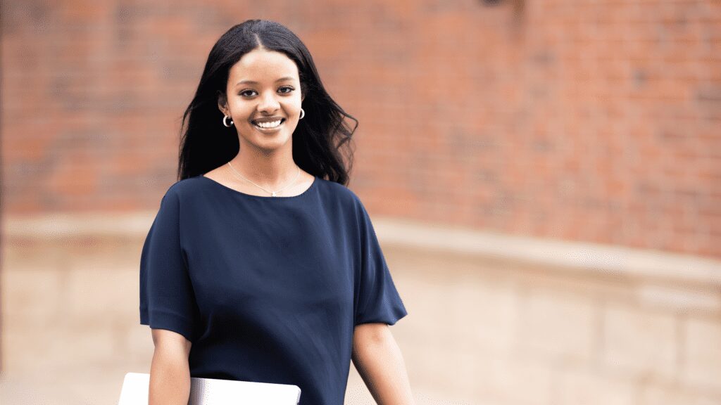 Woman holding a laptop walking outside.