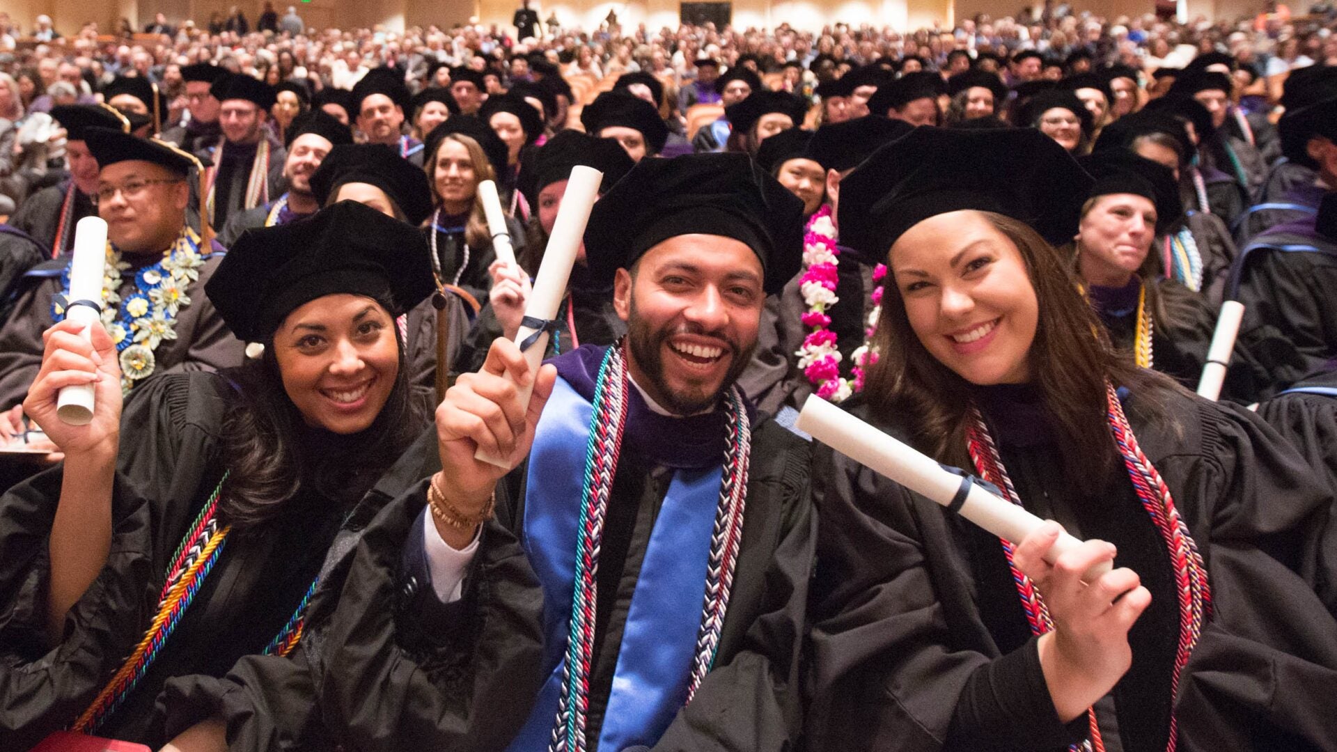 Happy graduates holding diplomas.