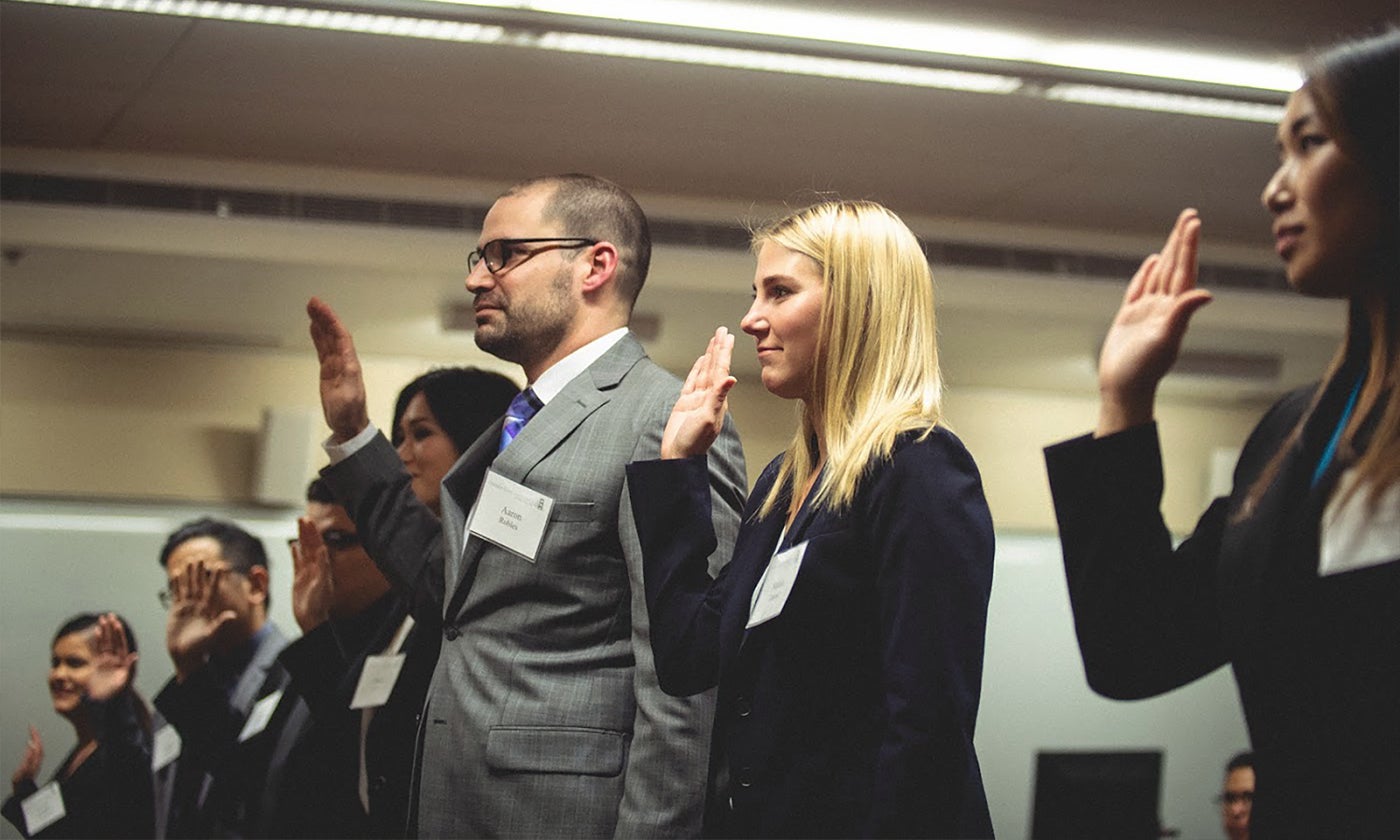 Group of professionals holding hand up taking an oath.
