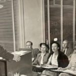 Students in class listening to teacher at podium in 1947.