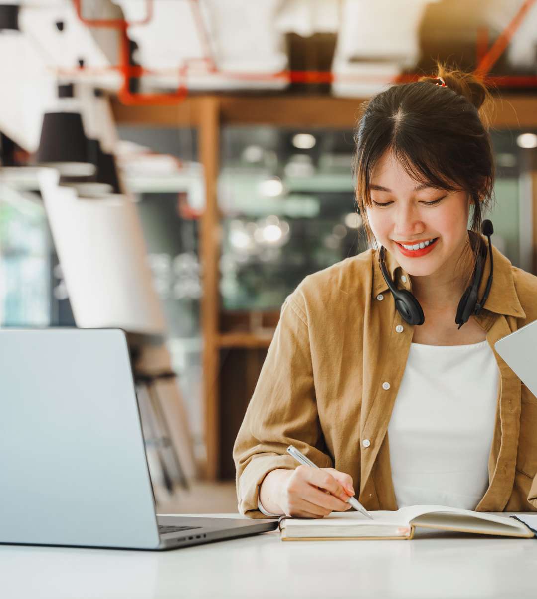 Woman sitting with laptop and notebook.