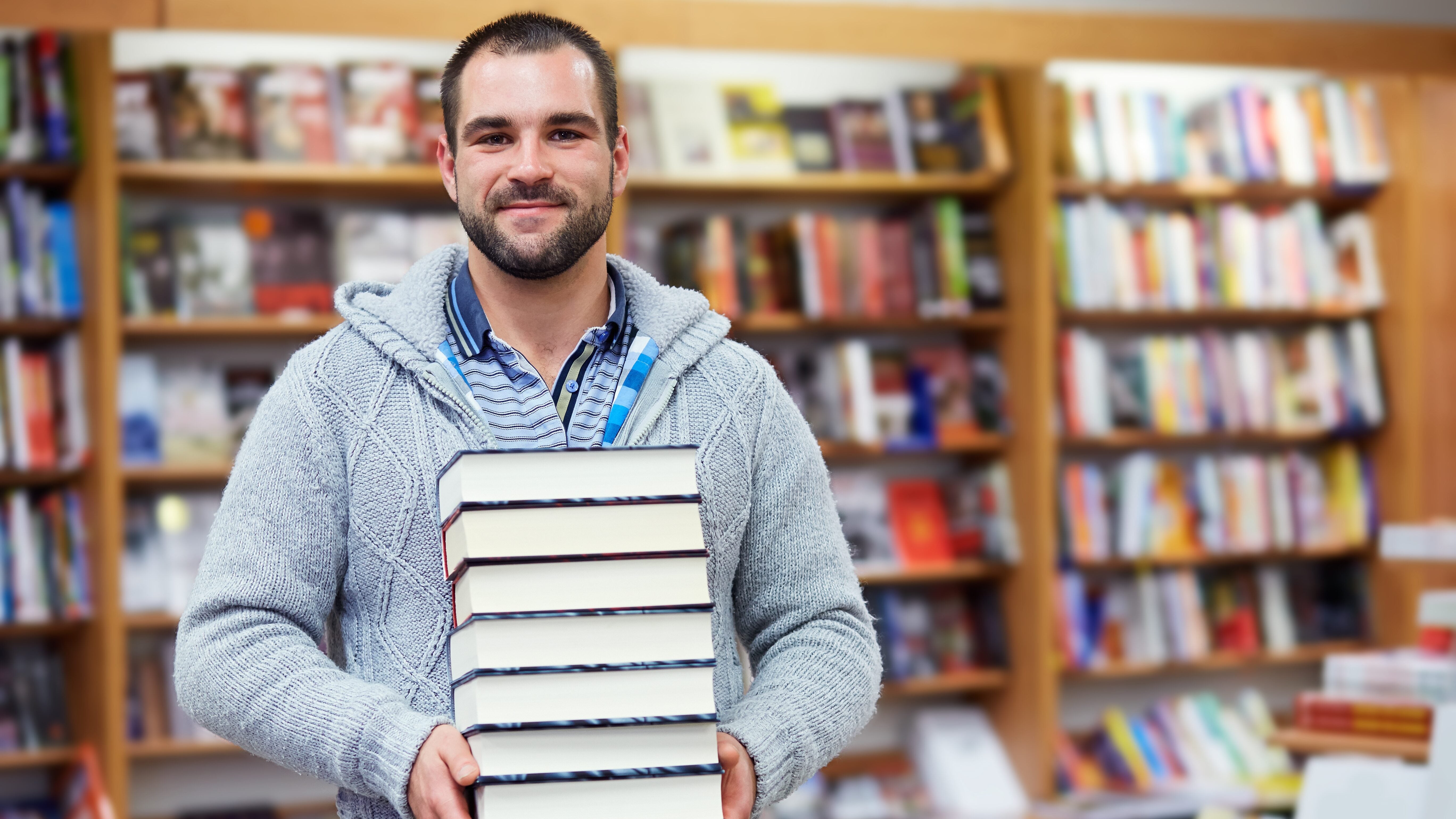 Student with stack of books in the bookstore.