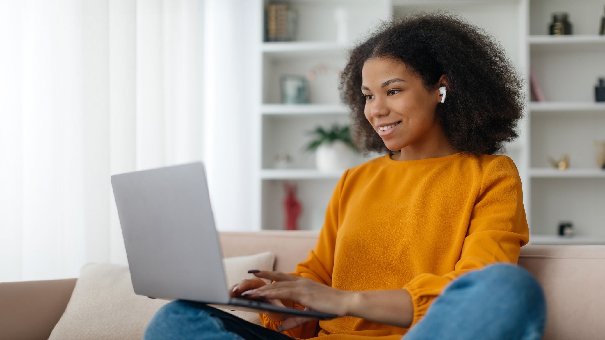 Woman sitting on couch with a laptop.