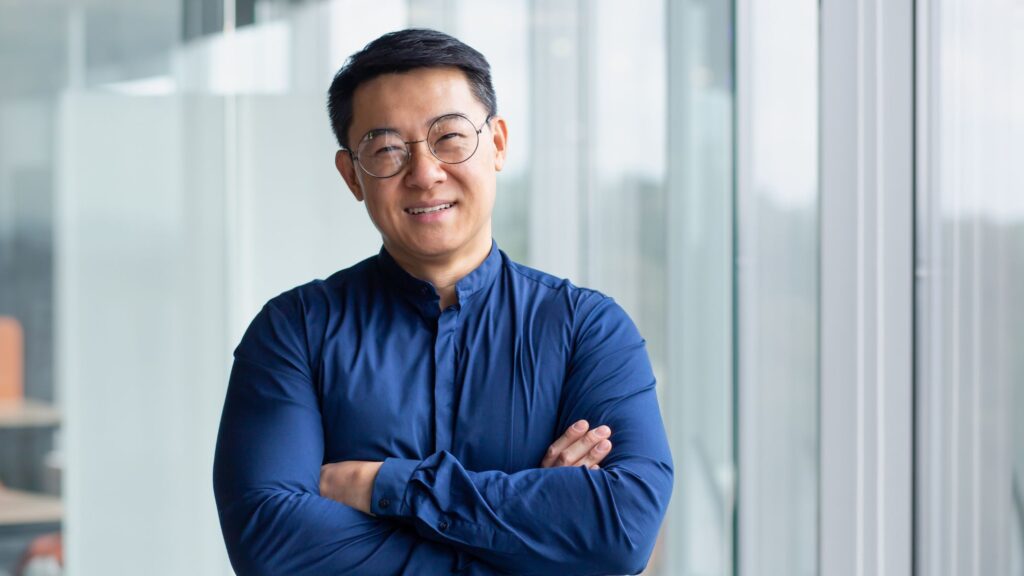 Smiling man standing with arms crossed.