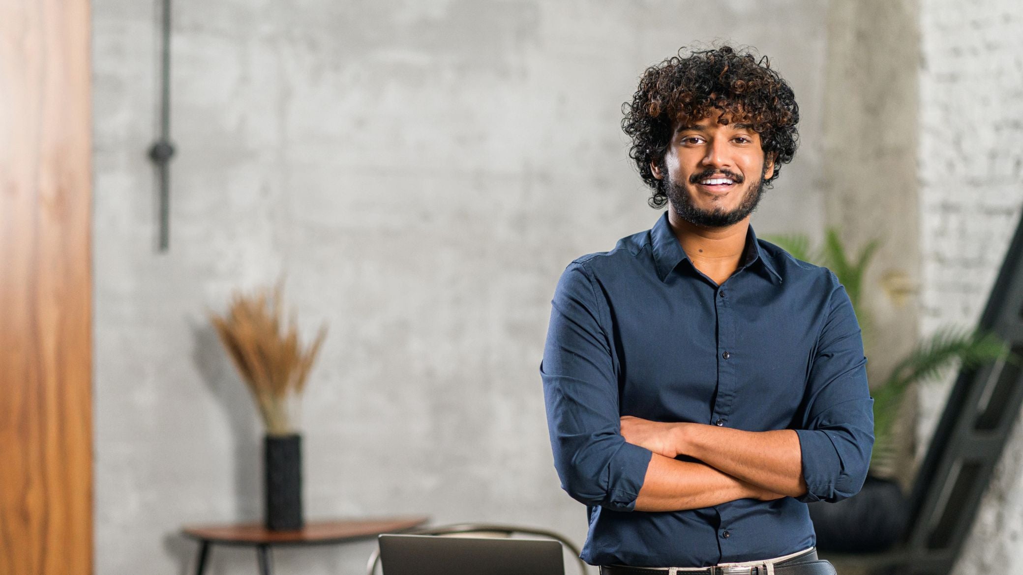 Smiling man standing with arms crossed.