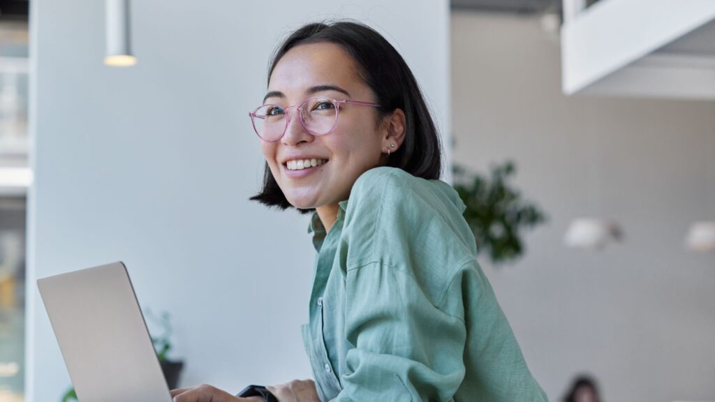 Smiling woman sitting in front of a laptop.