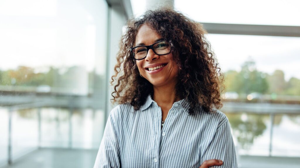 Smiling woman standing with arms crossed.
