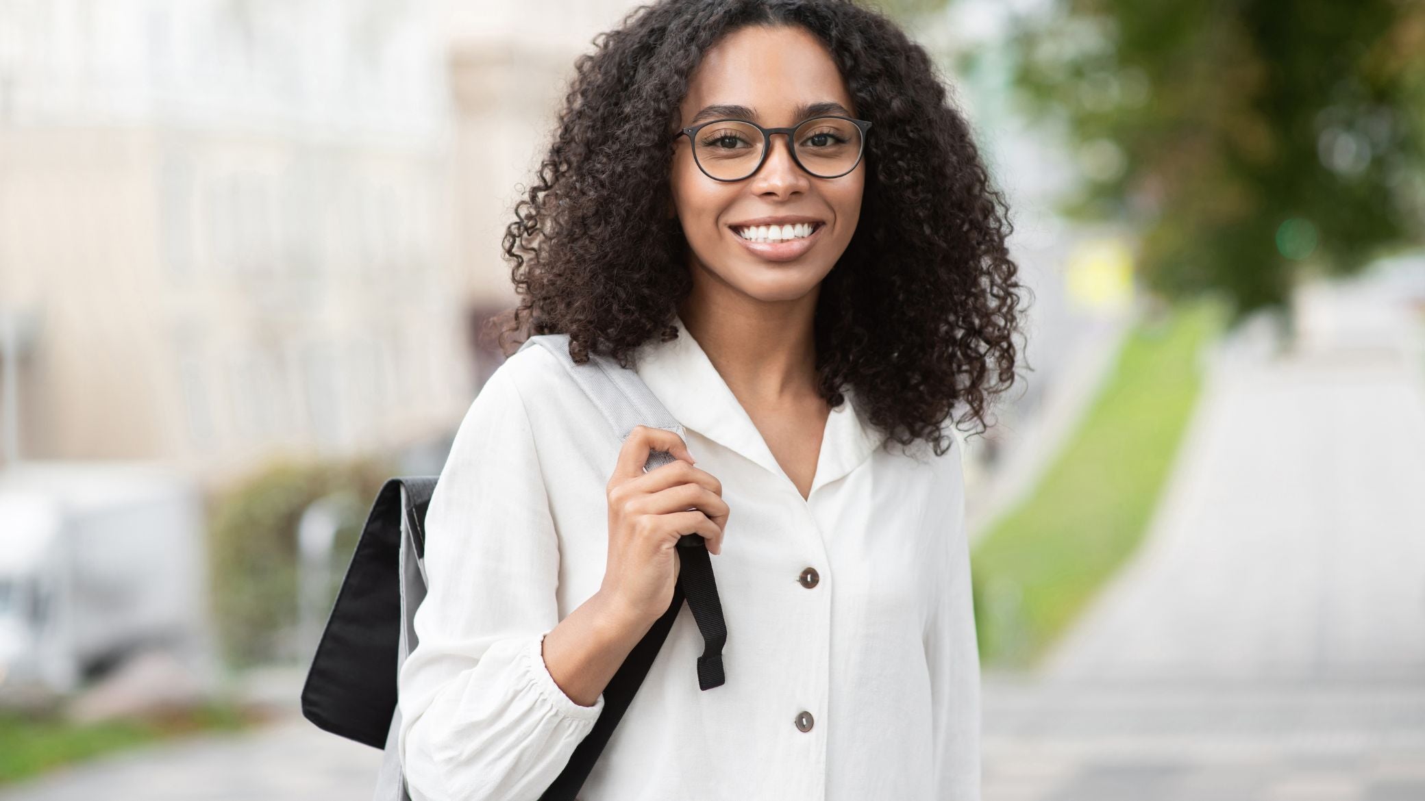 Smiling woman standing outside and wearing a backpack.