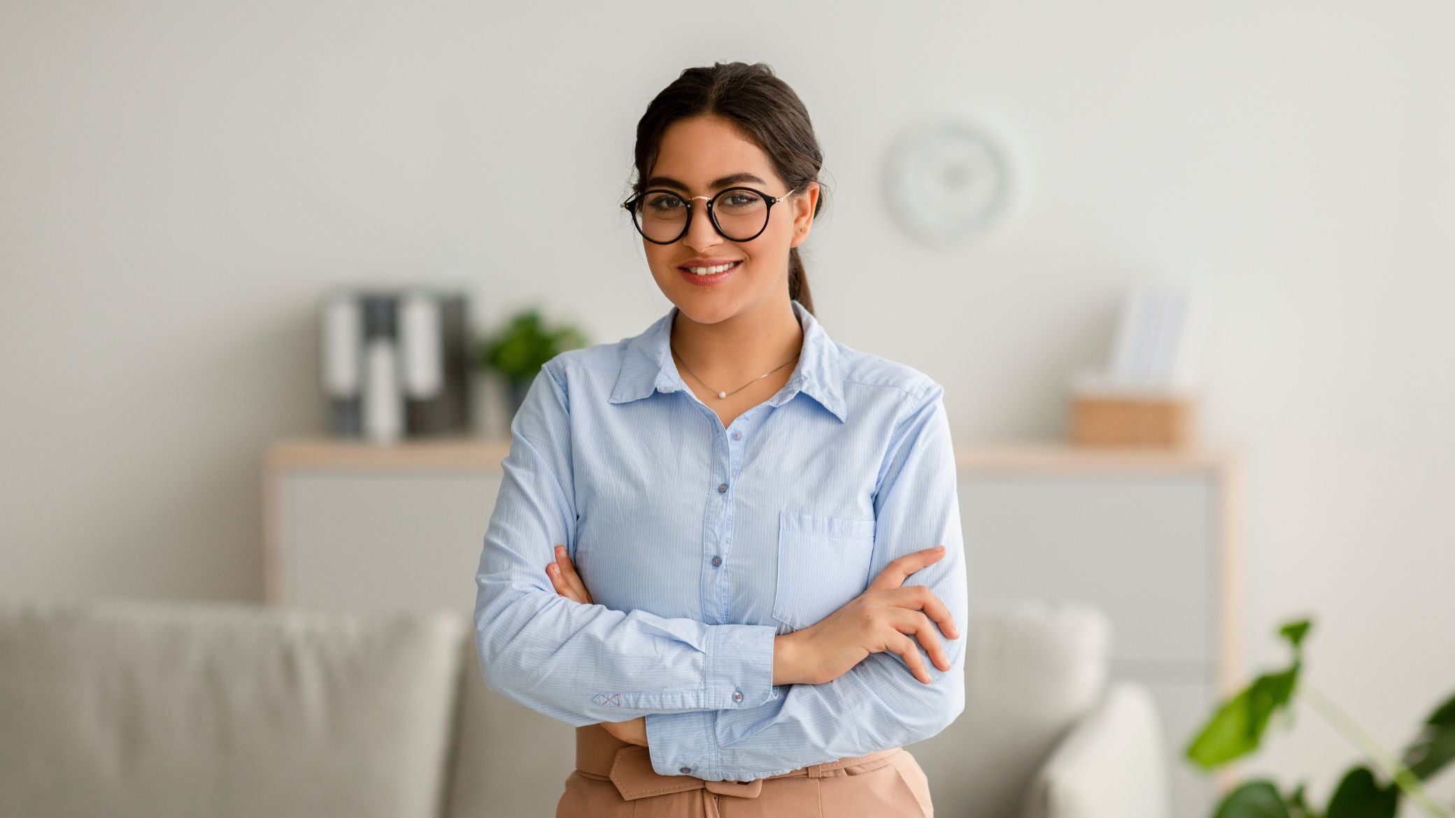 Smiling woman standing with arms crossed.